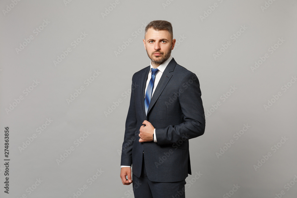 Handsome successful confident young business man in classic black suit shirt posing isolated on grey wall background, studio portrait. Achievement career wealth business concept. Mock up copy space. Handsome successful confident young business man in classic black suit shirt posing isolated on grey wall background, studio portrait. Achievement career wealth business concept. Mock up copy space.