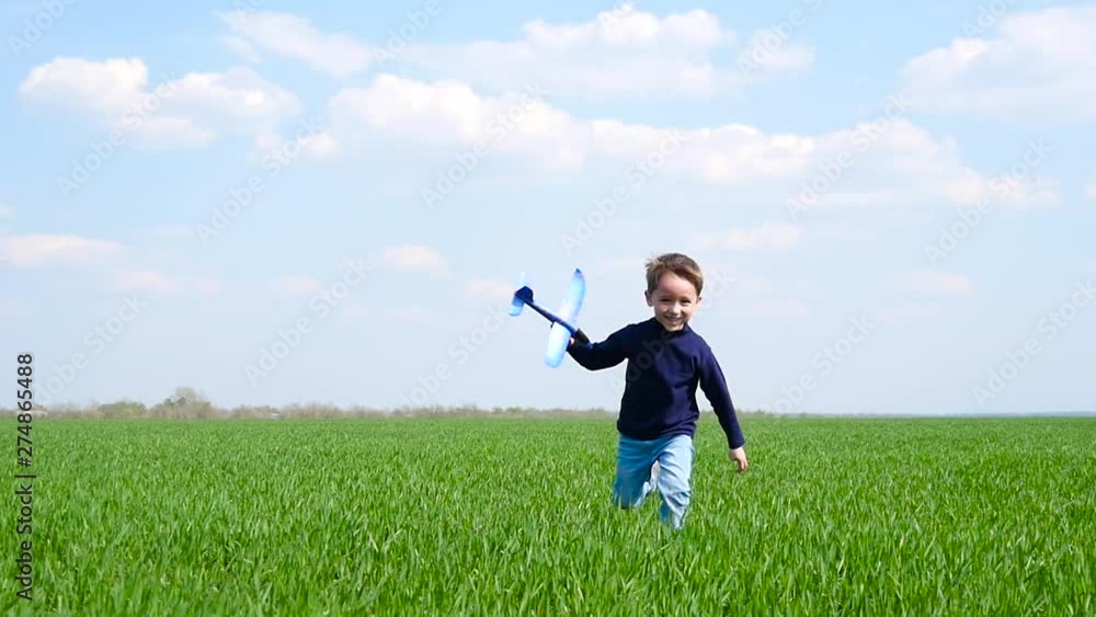 A happy child runs across a green lawn, holding a toy plane A happy child runs across a green lawn, holding a toy plane