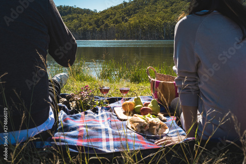 couple having picnic lunch on lake park in Autumn sunny day weekend leisure 
