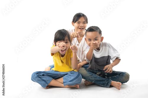 portrait of funny Asian Thai cute kids sitting pointing isolated on white background
