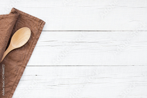 White wooden background with brown linen napkin and spoon