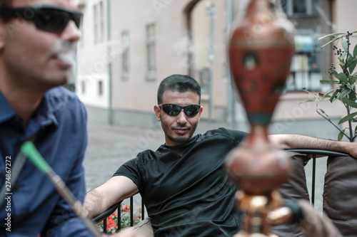 non-smoking person in the company of hookah smokers in a street European cafe.