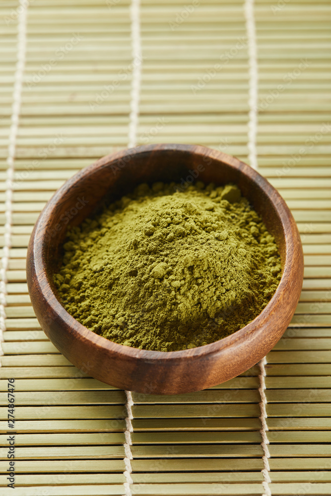 selective focus of green matcha powder in wooden bowl on bamboo table mat selective focus of green matcha powder in wooden bowl on bamboo table mat