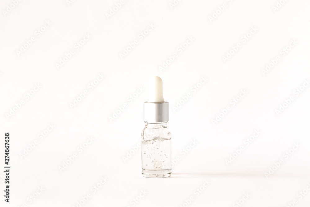 Cosmetic or medical bottle with pipette on white background. Oily drop falls from cosmetic pipette. Cosmetic or medical bottle with pipette on white background. Oily drop falls from cosmetic pipette.
