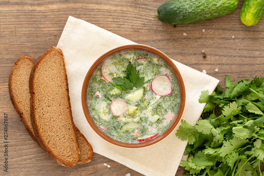 Summer yogurt cold soup with radish, cucumber, and dill on wooden table. Russian cold vegetable soup on yogurt. Okroshka. Summer yogurt cold soup with radish, cucumber, and dill on wooden table. Russian cold vegetable soup on yogurt. Okroshka.