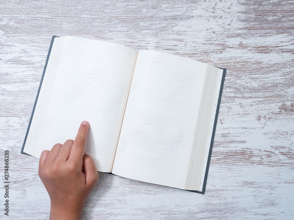 Finger pointing on a blank page of a book with copy space ready for text, isolated, wooden background Finger pointing on a blank page of a book with copy space ready for text, isolated, wooden background