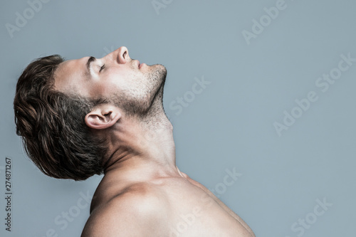 Male beauty concept. Portrait of handsome young man with stylish haircut posing over gray background. Perfect hair & skin. Tough guy. Vogue style. Close up. Studio shot
