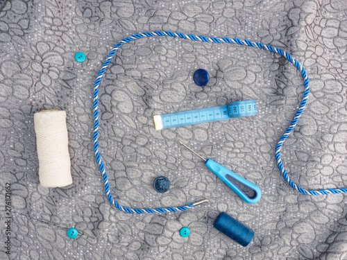 Tailor's tools - threads, awl, cord, buttons on a background of gray fabric. Stitching still life photo