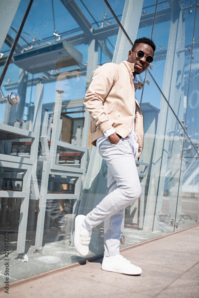 Handsome black young man in a jacket and white shirt on the street. Businessman