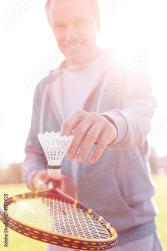 Active senior man playing badminton with tennis racket in park