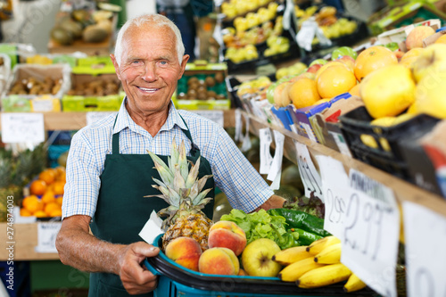 Elderly salesman working in greengrocery