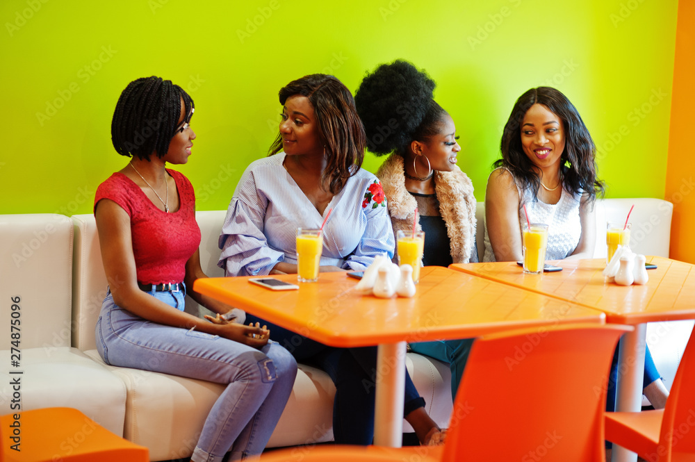 Four young african girls with juices sitting in bright colored fast food restaurant. Four young african girls with juices sitting in bright colored fast food restaurant.