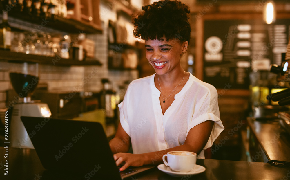 Smiling coffeeshop owner using laptop Smiling coffeeshop owner using laptop
