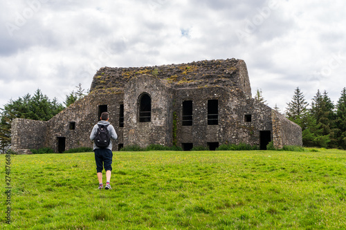 Photography Man hiker with a backpack walking towards the iconic Hellfire Club ruins on Montpelier Hill in Dublin, Ireland on cloudy summer day