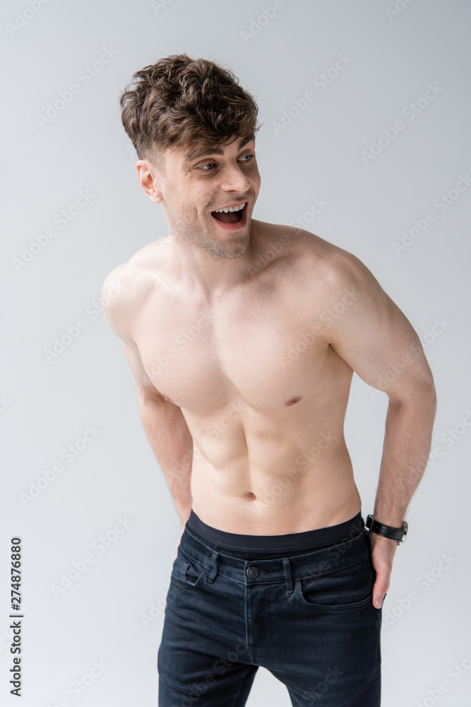 laughing shirtless muscular man looking away isolated on grey