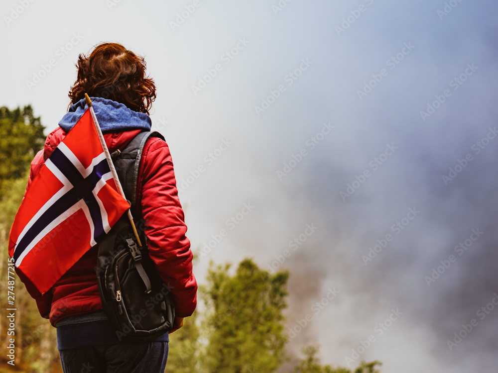 Tourist with norwegian flag in hazy mountains
