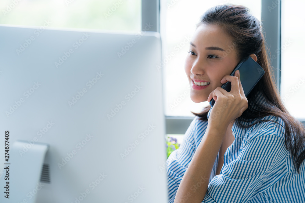 Young Asian woman entrepreneur/ Business owner using smart phone working with computer at home Young Asian woman entrepreneur/ Business owner using smart phone working with computer at home
