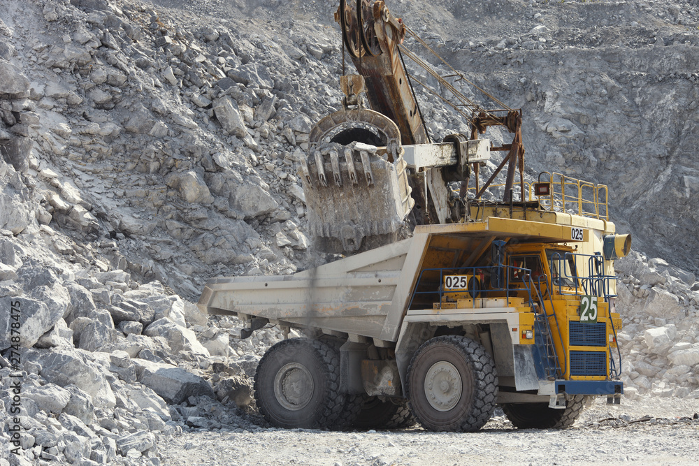 Excavator and truck in a quarry for limestone mining, close-up. Mining industry. Quarry mining equipment. Excavator and truck in a quarry for limestone mining, close-up. Mining industry. Quarry mining equipment.