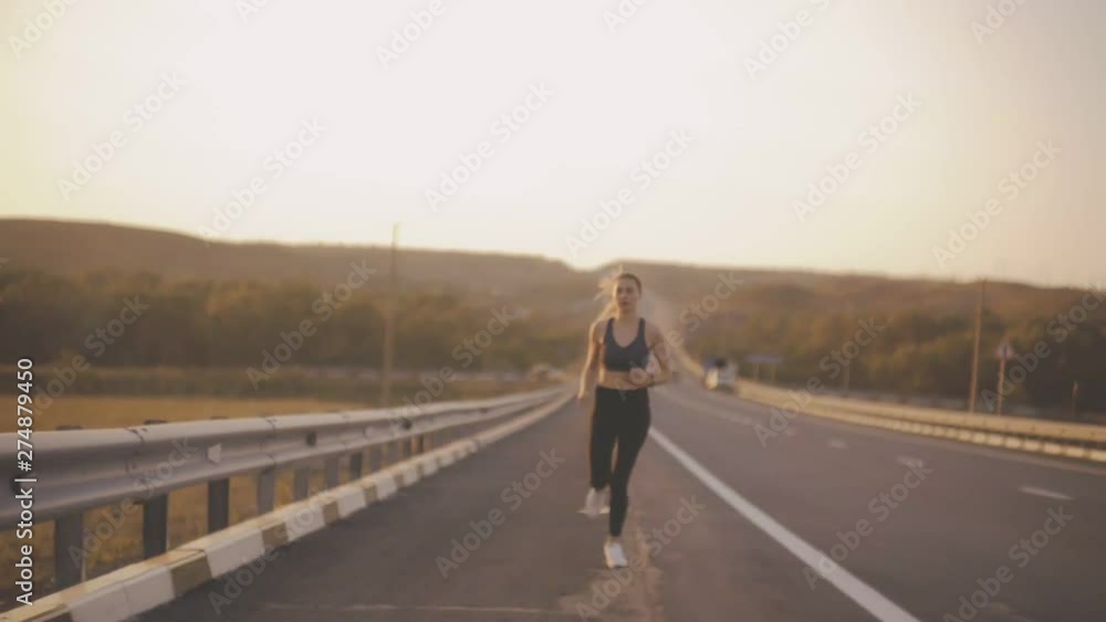 Girl Caucasian appearance, engaged in sport Jogging on the highway, overcomes fatigue Girl Caucasian appearance, engaged in sport Jogging on the highway, overcomes fatigue