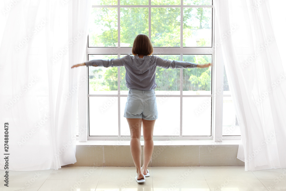 Morning of beautiful young woman near window