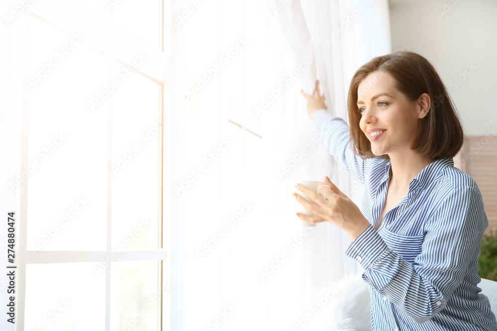Morning of beautiful young woman drinking coffee near window Morning of beautiful young woman drinking coffee near window