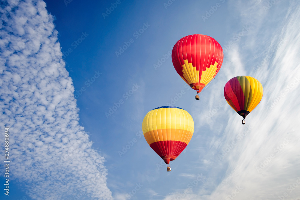 Naklejka premium Colourful hot air balloons flying over white clouds and blue sky.
