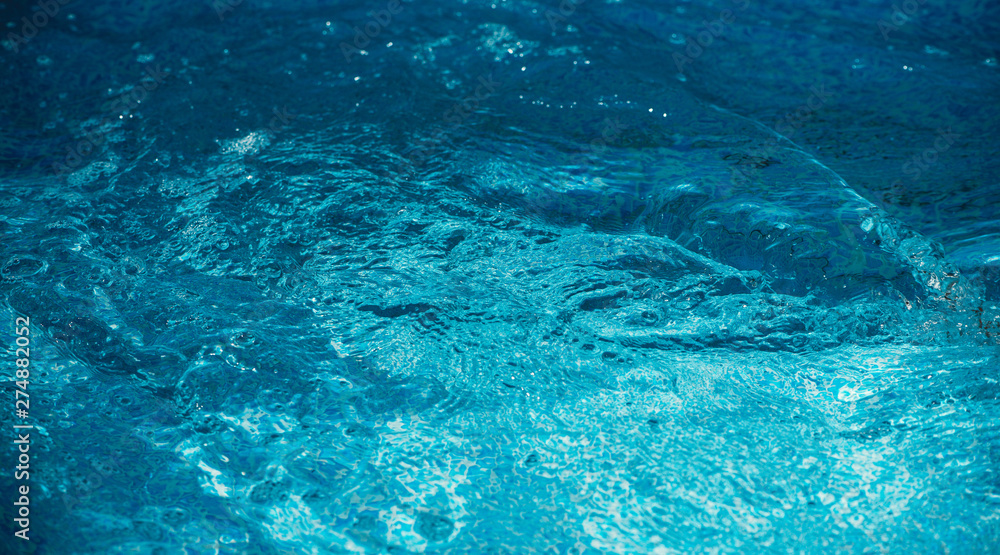 Blue and bright water in swimming pool with sun reflection. Motion of ripple water and  wave in pool, background.