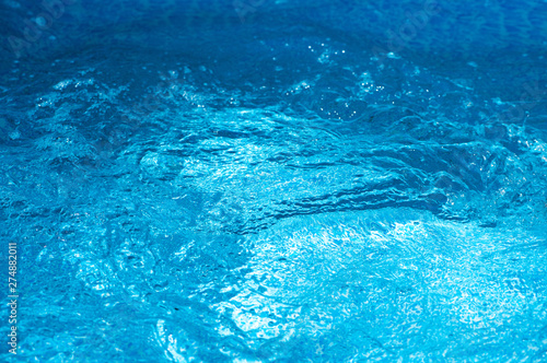 Blue and bright water in swimming pool with sun reflection. Motion of ripple water and wave in pool, background.