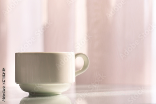 Coffee cup on white table with reflection. Morning coffee concept.