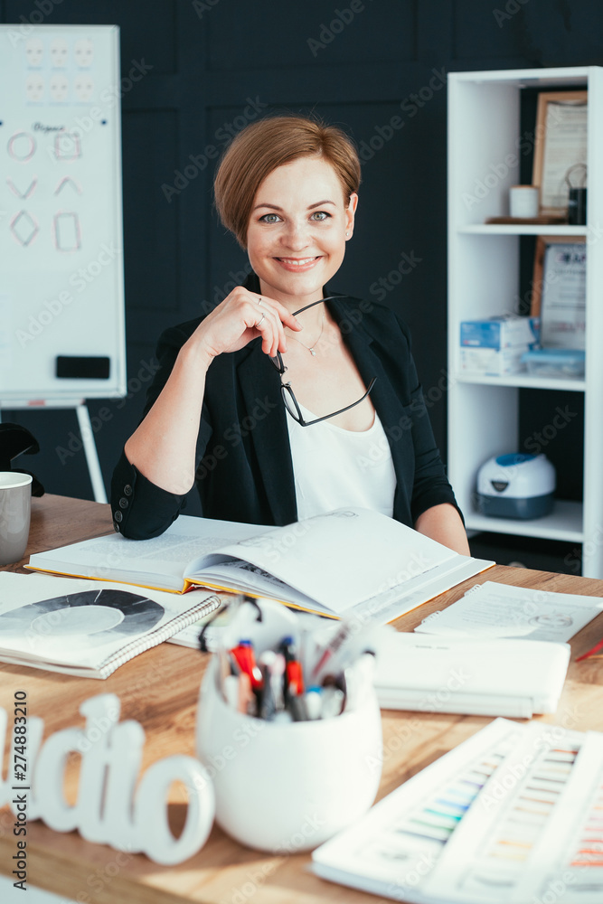 Fototapeta premium Young businesswoman sitting on the desk in workshop studio