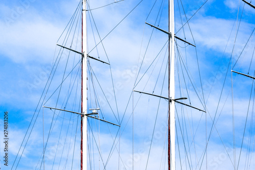 Ship masts and blue sky with clouds on background. 