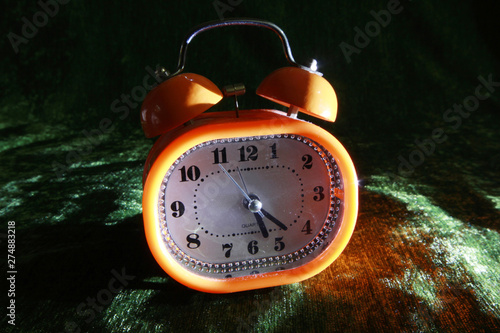 orange alarm clock on velvet fabric