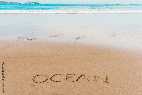 Ocean (inscription) on the beach (sand) by the sea or ocean. Summer mood concept.