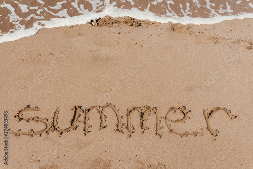 Summer (inscription) on the beach (sand) by the sea or ocean. Summer mood concept.
