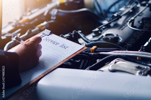 Car care, car mechanic are waiting to check the engine and record the information on the service list.