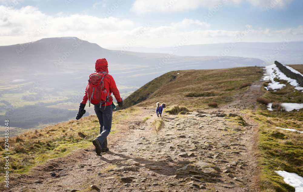 A hiker walking down from the summit of Whernside, part of the Three Peaks in the Yorkshire Dales, England.