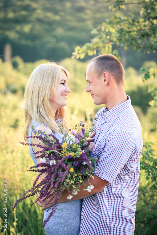 Man and woman on nature with a bouquet of flowers. Couple in love. Man and woman on nature with a bouquet of flowers. Couple in love.