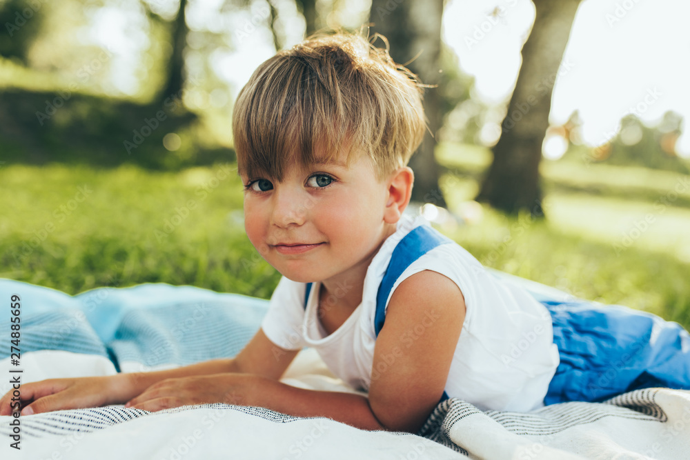 Cute little boy lying on the blanket and looking to the camera