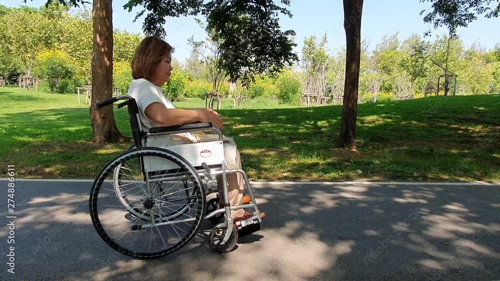Senior woman on wheelchair relaxing in the park Senior woman on wheelchair relaxing in the park