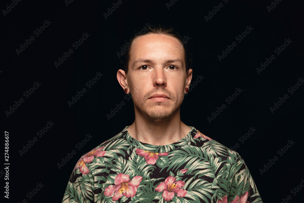 Close up portrait of young caucasian man isolated on black studio background. Photoshot of real emotions of male model. Standing and looks serious. Facial expression, human nature and emotions concept Close up portrait of young caucasian man isolated on black studio background. Photoshot of real emotions of male model. Standing and looks serious. Facial expression, human nature and emotions concept
