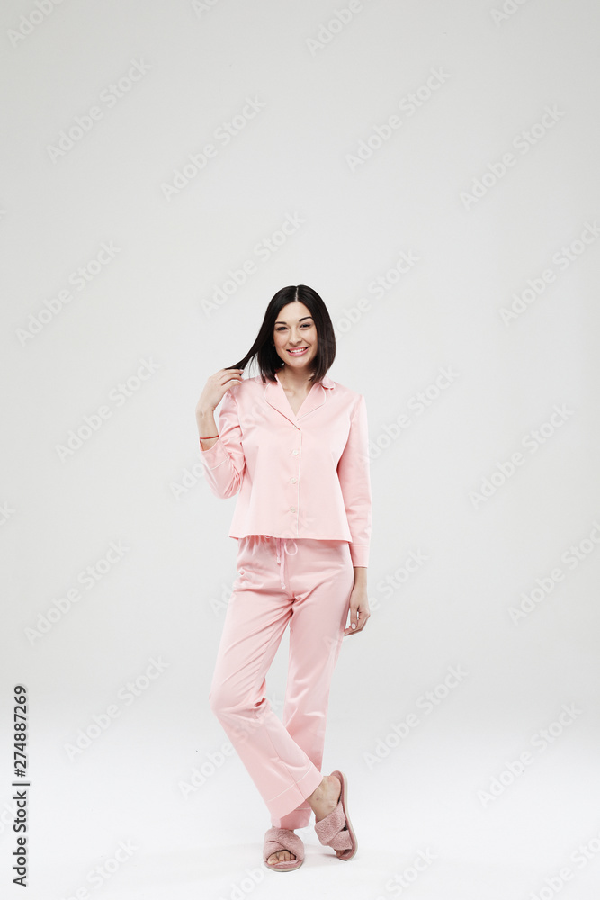 lifestyle, fashion, and people concept - beautiful brunette girl dressed in pink pajamas over white background