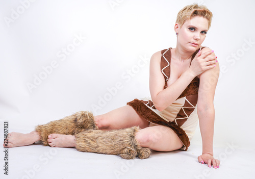 Fotografie hot plus size woman in fur carnival costume of primitive man on white background in Studio