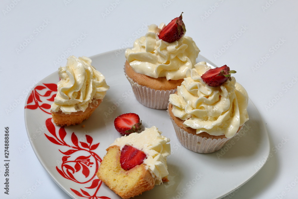 Cupcakes with strawberries and butter cream. One is cut in half. Visible filling. Cupcakes with strawberries and butter cream. One is cut in half. Visible filling.