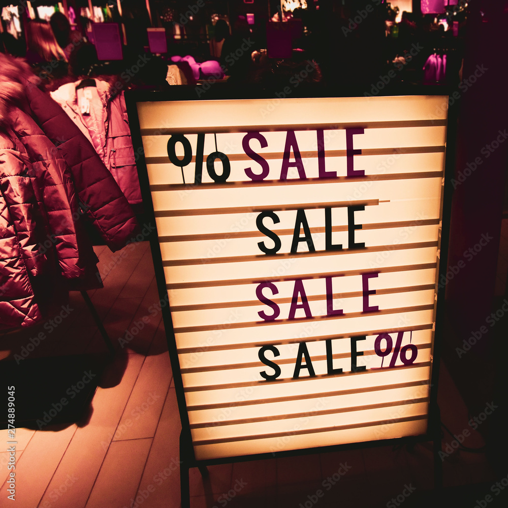 Stylish vintage sign. SALE in a showcase of a clothing store. Beautiful yellow lights