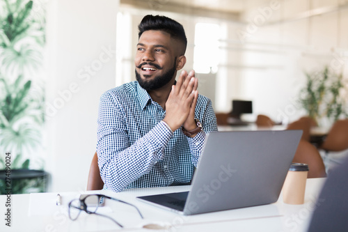 Young Asian Indian businessman working on laptop in modern office photo