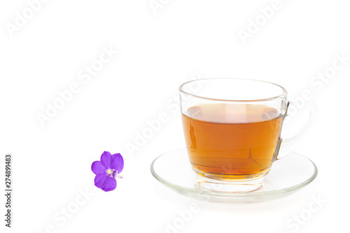 Tea in a glass cup with purple flower isolated in white background.