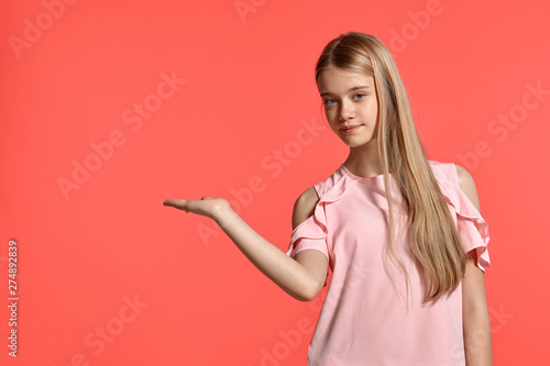 Studio portrait of a beautiful girl blonde teenager in a rosy t-shirt posing on pink background.
