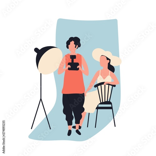 Professional female photographer holding photo camera and model at photographic studio full of photography equipment