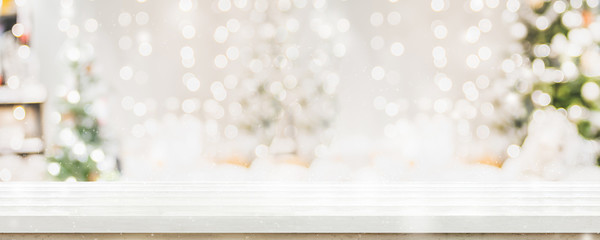 Empty white wold table top with abstract warm living room decor with christmas tree string light blur background with snow,Holiday backdrop,Mock up banner for display of advertise product.