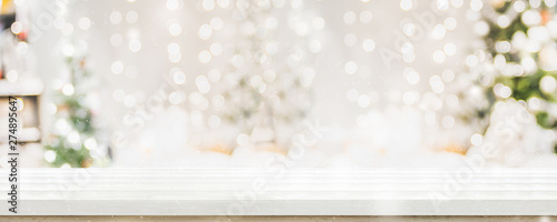 Empty white wold table top with abstract warm living room decor with christmas tree string light blur background with snow,Holiday backdrop,Mock up banner for display of advertise product.